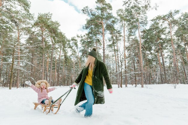 Mooie jongedame met klein meisje plezier buiten in winter park