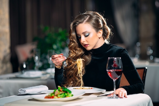 Mooie jongedame pasta eten in een restaurant