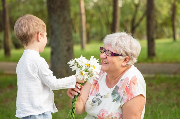 Mooie jongen die een bloem geeft aan oma. Gelukkige Moederdag.