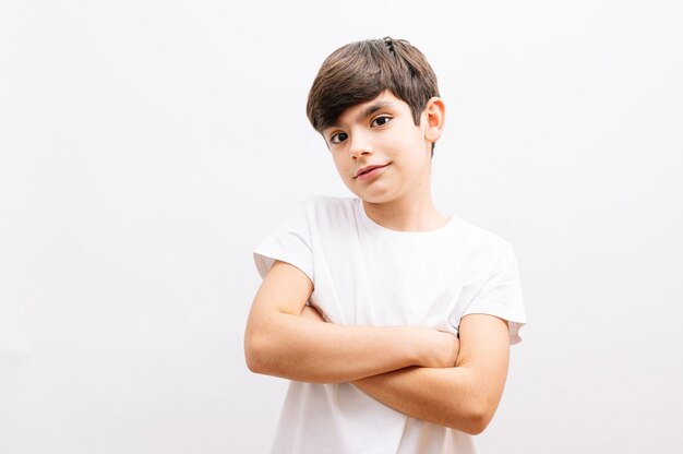 Mooie jongen jongen draagt grijs casual t-shirt staande over geïsoleerde witte achtergrond blij gezicht lachend met gekruiste armen kijken naar de camera. Positieve persoon.