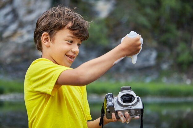 Mooie jongen reinigt CMOS-beeldsensor in DSLR-camera met zeepsop en water uit de rivier.