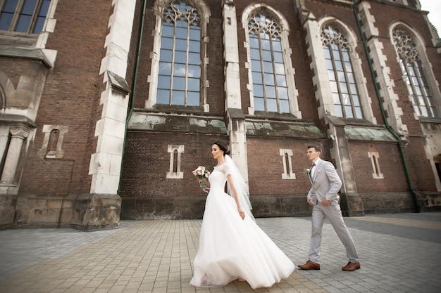 Mooie jonggehuwde paar wandeling in de buurt van oude christelijke kerk