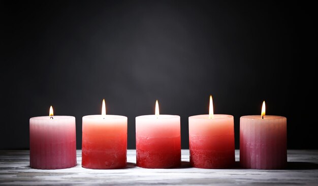 Mooie kaarsen met bloemen op houten tafel, op donkere achtergrond