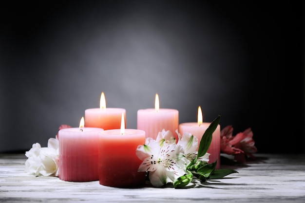 Mooie kaarsen met bloemen op houten tafel, op donkere achtergrond
