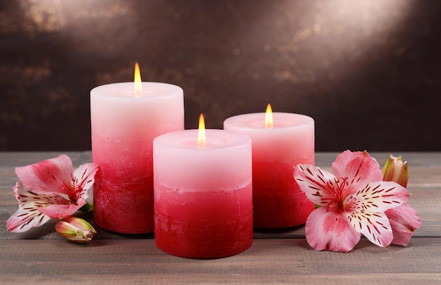 Mooie kaarsen met bloemen op tafel op bruine achtergrond