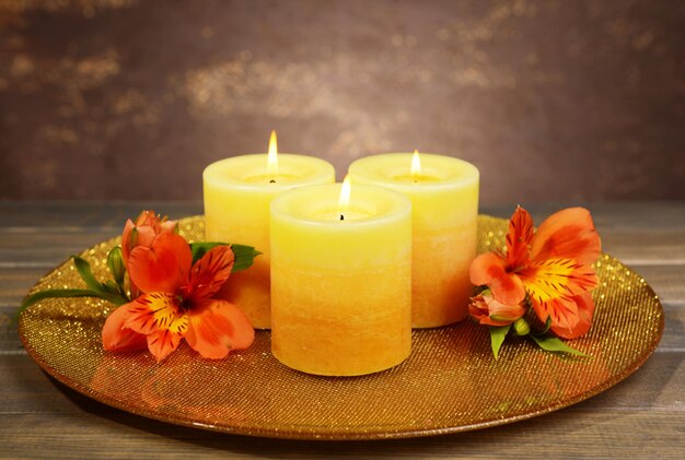 Mooie kaarsen met bloemen op tafel op bruine achtergrond