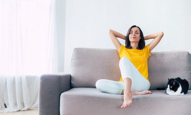 Mooie kalme zelfverzekerde brunette vrouw rust tijdens de vakantie thuis op de bank