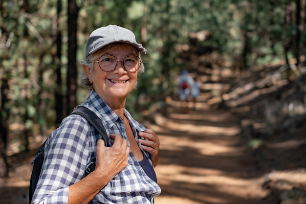 Mooie Kaukasische senior vrouw met hoed en rugzak wandelen het pad op een bergwandeling genieten van vrije tijd en vrijheid in de natuur senior gepensioneerde dame en gezonde levensstijl concept