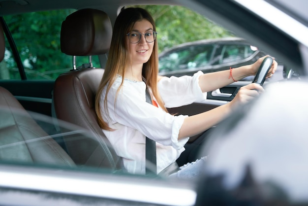 Mooie kaukasische vrouw die nieuwe auto drijft die camera bekijkt. vervoersconcept: