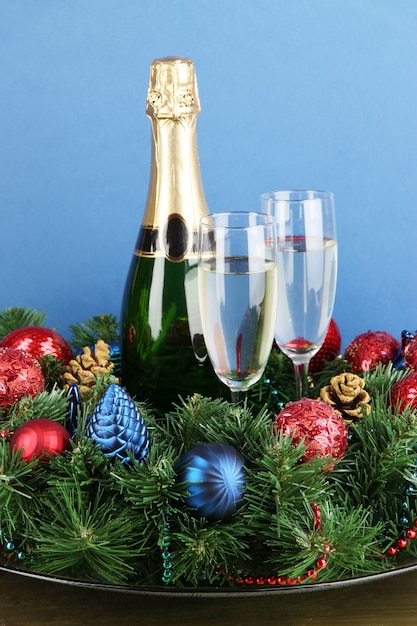 Mooie kerstkrans in compositie met champagne op blauwe achtergrond