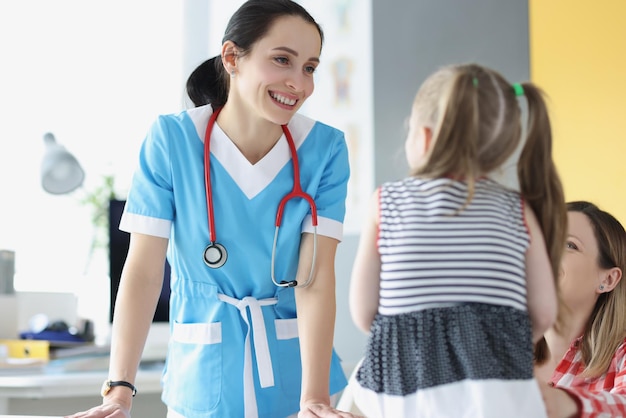 Mooie kinderarts aan het chatten met een schattig geduldig kindmeisje op afspraak in de kliniek