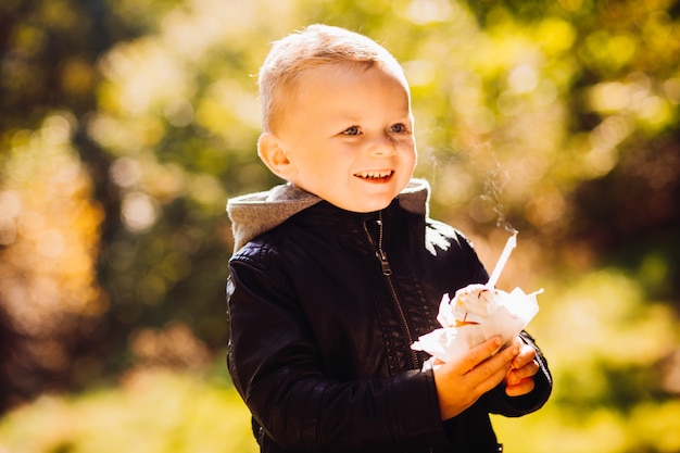 Mooie kleine jongen staat in een herfst park in een zonnige dag