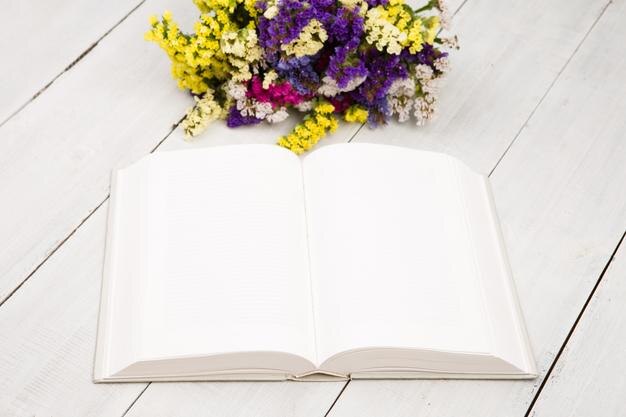 Mooie kleurrijke bloemen en open blanco boek op een witte houten tafel