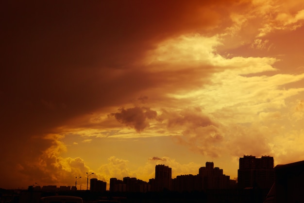 Mooie kleurrijke dramatische zonsonderganghemel met stormachtige wolken over silhouet van de stad