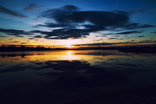 Mooie kleurrijke oranje-blauwe hemel bij zonsondergang over het meer