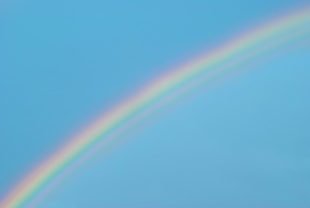 Mooie kleurrijke regenboog in de blauwe lucht