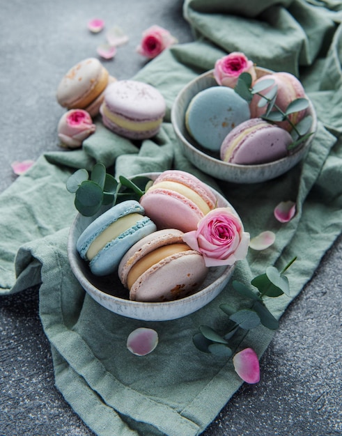 Foto mooie kleurrijke smakelijke bitterkoekjes en roze rozen op een betonnen achtergrond