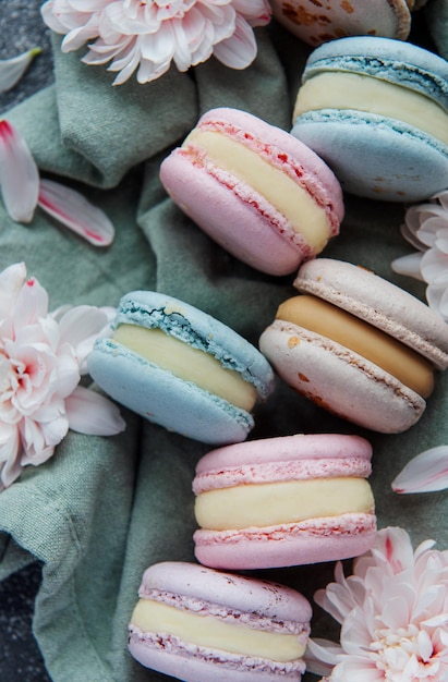 Mooie kleurrijke smakelijke bitterkoekjes en witte bloemen op een betonnen achtergrond