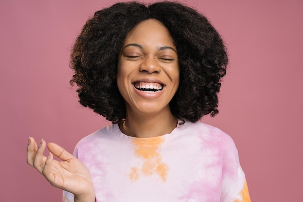 Foto mooie lachende afrikaanse vrouw draagt stropdas kleurstof t-shirt geïsoleerd op roze background