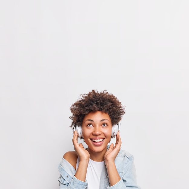 Mooie lachende Afro-Amerikaanse vrouw luistert naar muziek via een koptelefoon