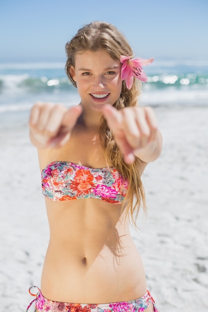 Mooie lachende blonde met bloem haartoebehoren op het strand