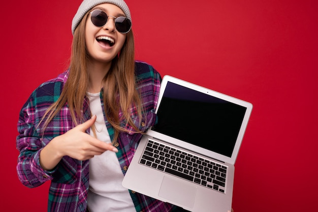 Mooie lachende grappige lachende blonde jonge vrouw met computerlaptop met leeg beeldscherm