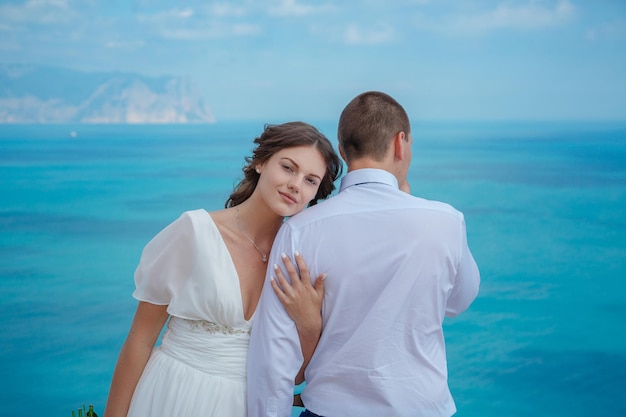 Mooie lachende jonge bruid en bruidegom wandelen op het strand zoenen en plezier hebben huwelijksceremonie in de buurt van de rotsen en de zee Huwelijksceremonie aan de kust van Cyprus