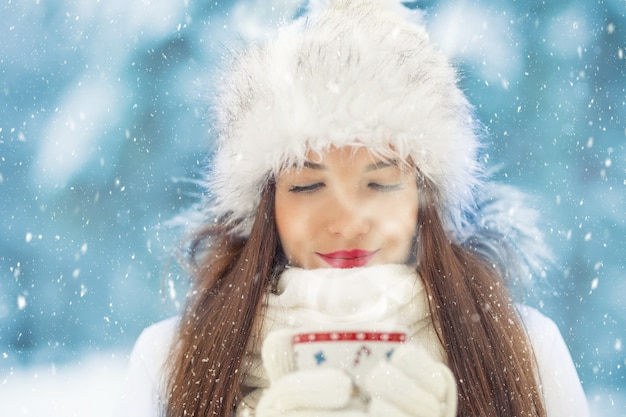 Mooie lachende jonge vrouw in warme kleding met kop warme drank