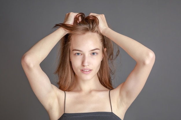 Mooie lachende jonge vrouw met perfecte huid gezicht natuurlijke schoonheid concept geïsoleerd op grijze studio background