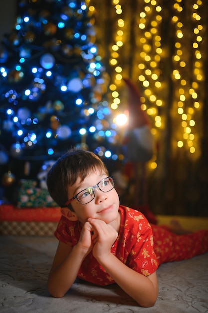 Mooie lachende kleine jongen in de buurt van de kerstboom