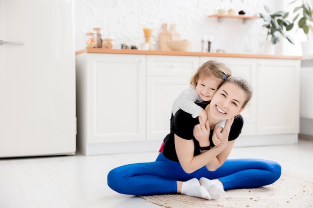 Mooie lachende moeder gaat sporten met haar dochter thuis