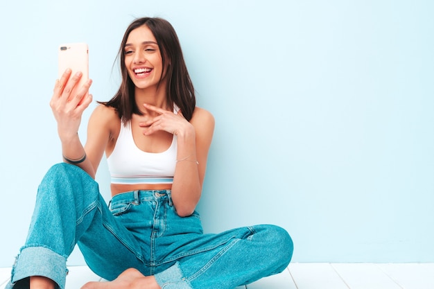 Mooie lachende vrouw gekleed in witte jersey top shirt en jeans. zorgeloos vrolijk model geniet van haar ochtend