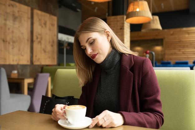 Mooie lachende vrouw koffie drinken in café.