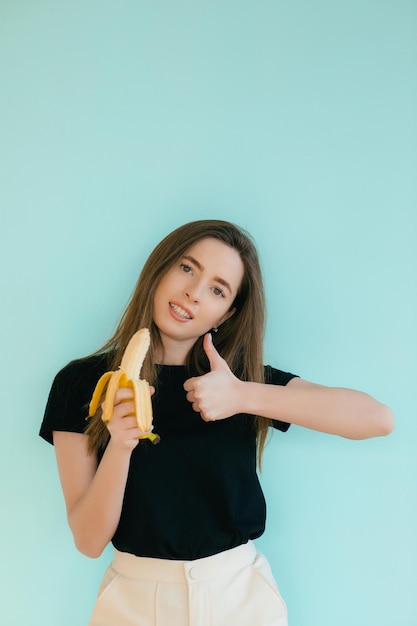 mooie lachende vrouw met banaan in de buurt van gezicht