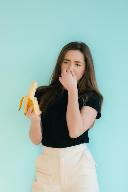 mooie lachende vrouw met banaan in de buurt van gezicht