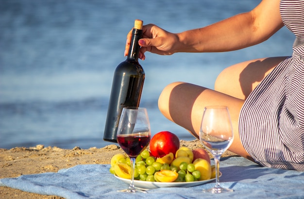 Mooie lachende vrouw met een glas wijn op het strand. fruitrode wijn.