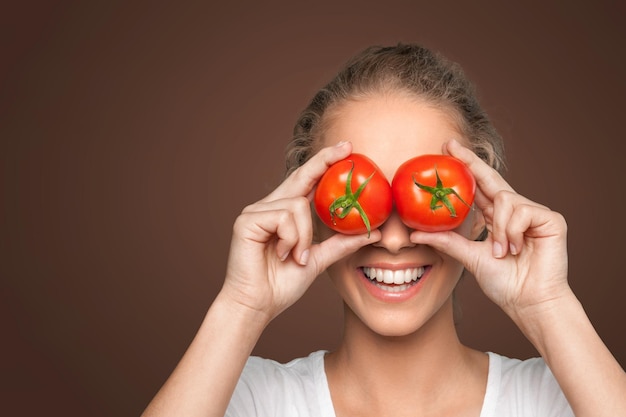 Mooie lachende vrouw met twee rijpe tomaten voor haar ogen.