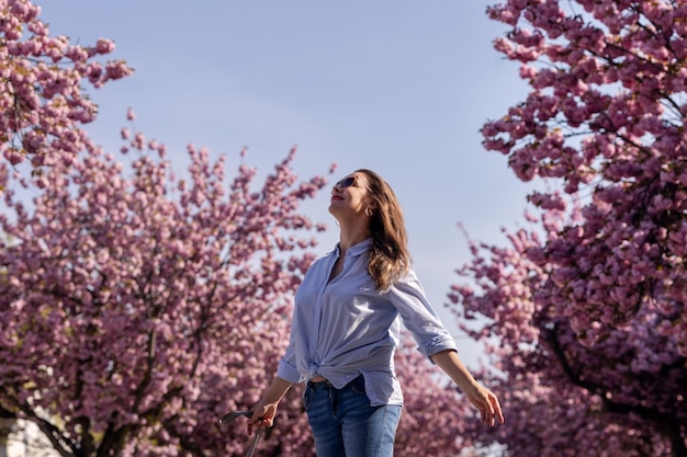 Mooie lachende vrouw op de achtergrond van lila roze kersenbloesems