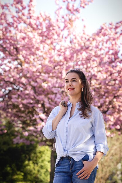 Mooie lachende vrouw op de achtergrond van lila roze kersenbloesems