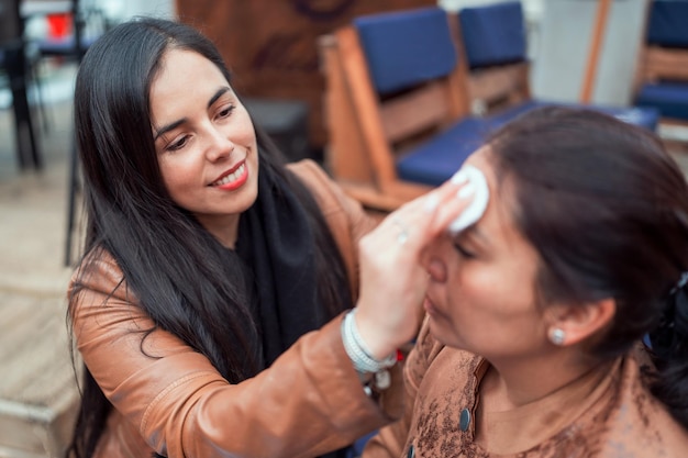 Mooie Latijns-rijpe vrouw die haar cliënt schoonmaakt of gezichtsbehandeling geeft