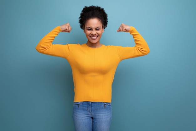 Foto mooie latijns-vrouw met afro haar in casual gele blouse poseren op studio achtergrond