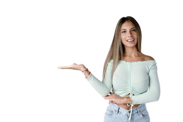 Mooie Latijnse vrouw kijkt ernaar uit met haar rechterarm uitgestrekt en haar hand open op een puur witte achtergrond. Studiofotografie.