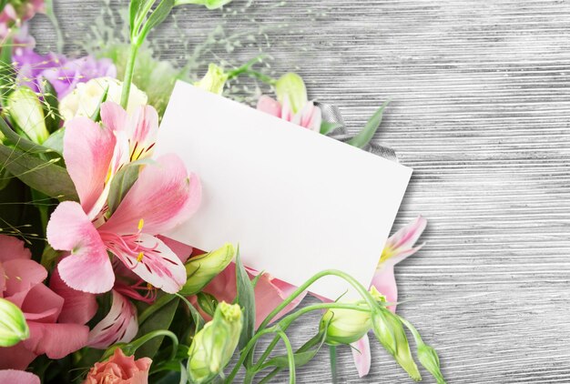 Foto mooie lelies bloemen boeket en blanco kaart op houten