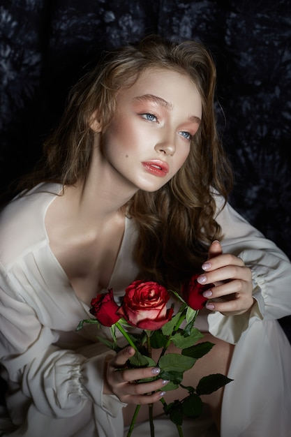 Mooie lente meisje zit op de vloer met roze bloemen in haar handen