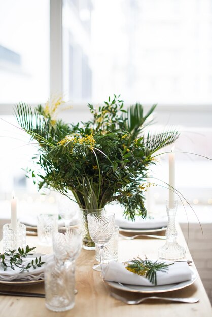 Mooie lentetafel met groene bladeren en mimosa takken