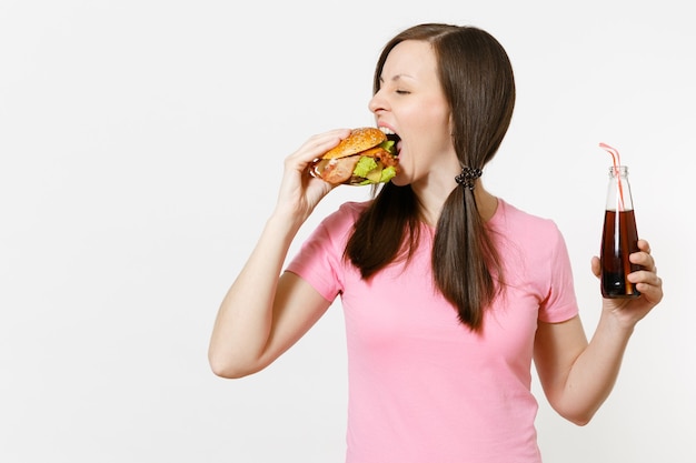 Mooie leuke jonge vrouw met staarten permanent en houden hamburger, cola in glazen fles geïsoleerd op een witte achtergrond. Goede voeding of Amerikaans klassiek fastfood. Advertentieruimte met kopieerruimte.