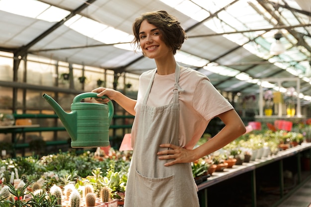 mooie leuke vrouw tuinman permanent over planten in kas water bloemen