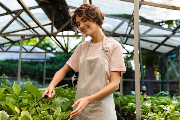 mooie leuke vrouw tuinman permanent over planten in kas