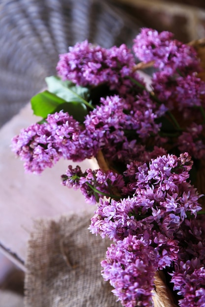 Mooie lila bloemen in rieten mand op kleur muur achtergrond