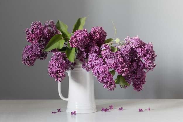 Mooie lila bloemen in witte kan op witte houten tafel wooden